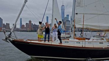 Party on the bow of a sailboat with the Manhattan Skyline