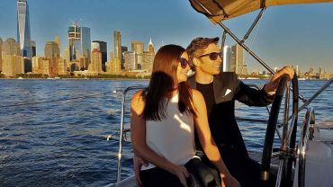 Romantic couple at the helm of a sailboat with Manhattan skyline